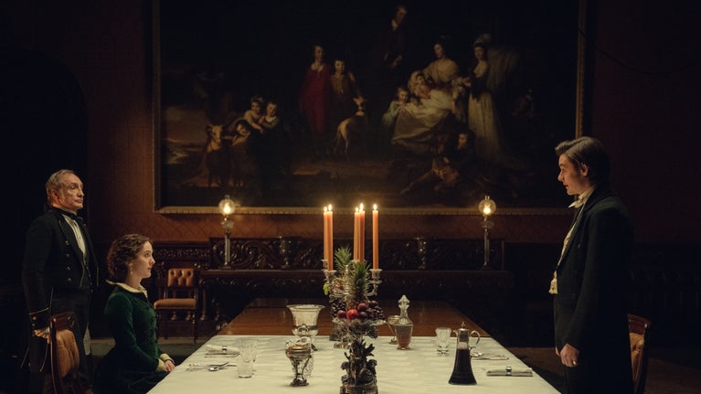 Three characters from the Netflix production 'House of Guinness' face each other across the Dining Room table at Penrhyn Castle